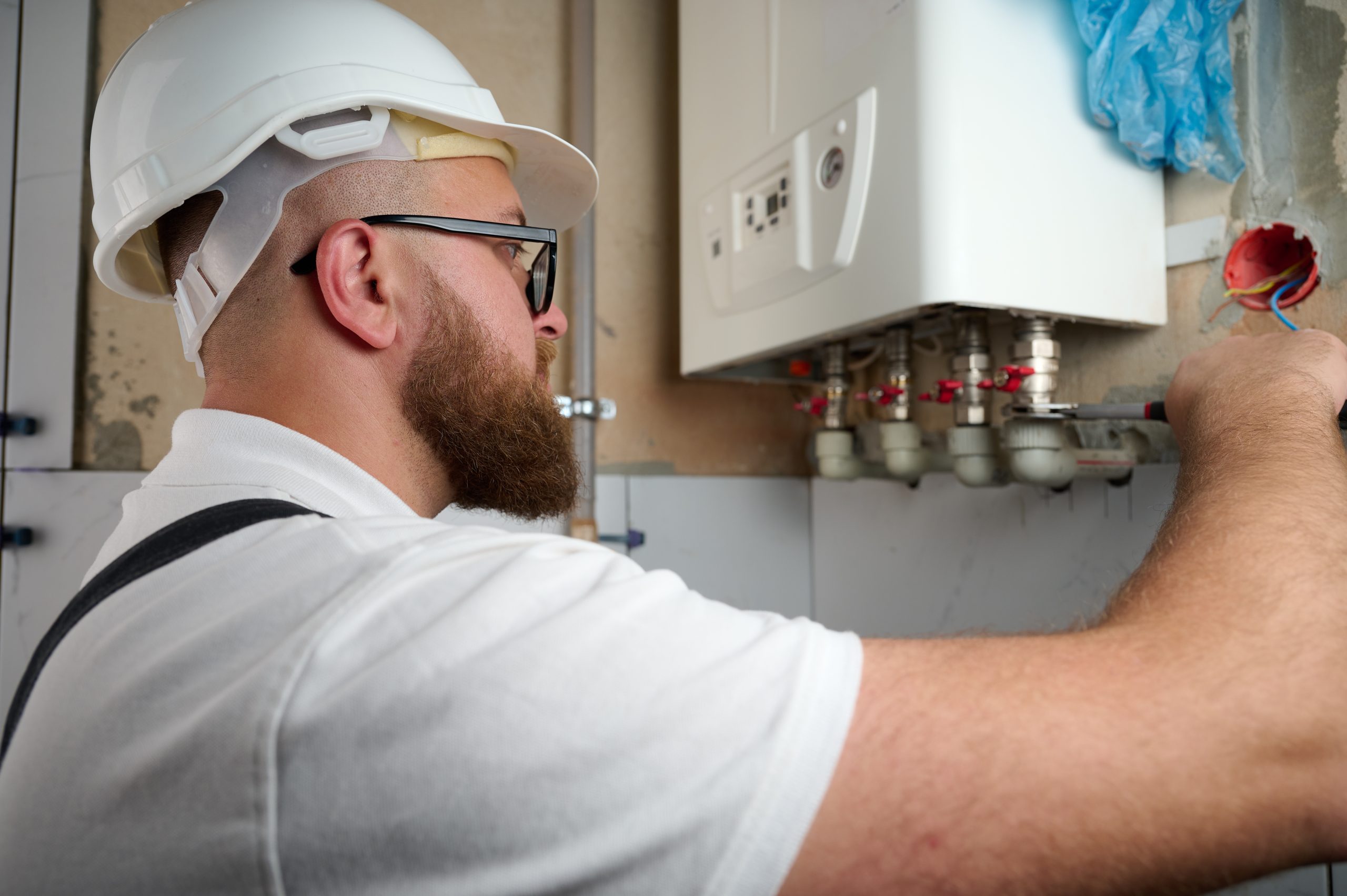 Plumber Install a Boiler. Professional engineer installing gas boiler at home and checking the connections and pipes of the domestic heating system. Boiler Installation Service adjusting heating system